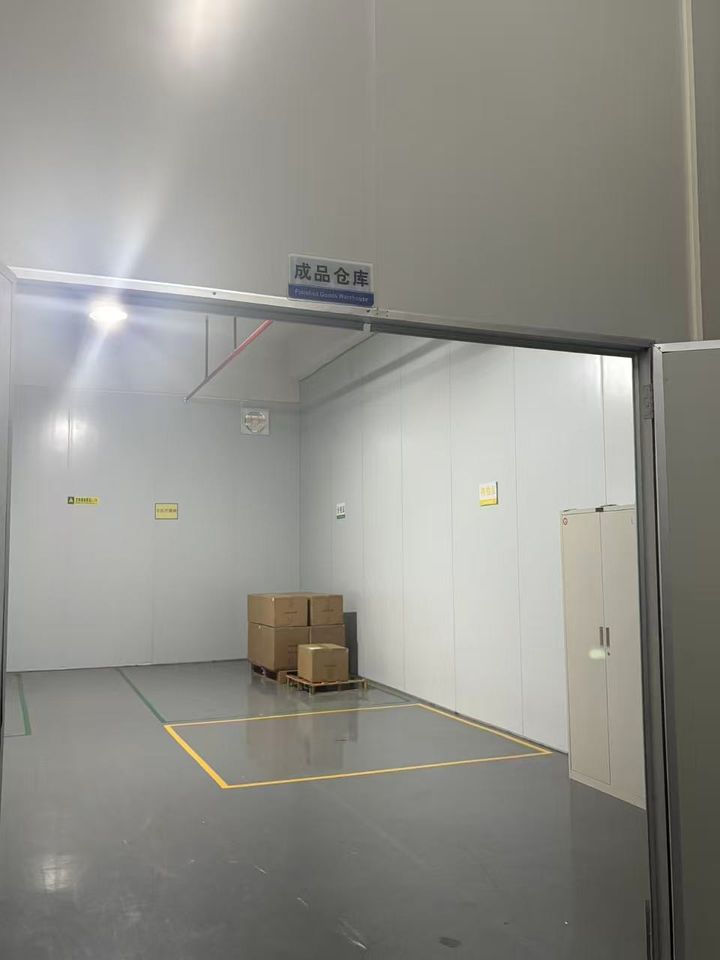 Finished-goods warehouse with a marked floor bay and cartons on a pallet.