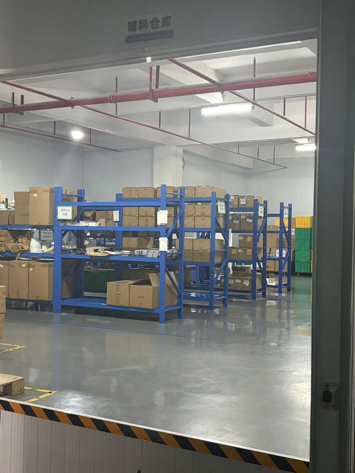 Auxiliary-materials warehouse with blue racking and labelled cartons.