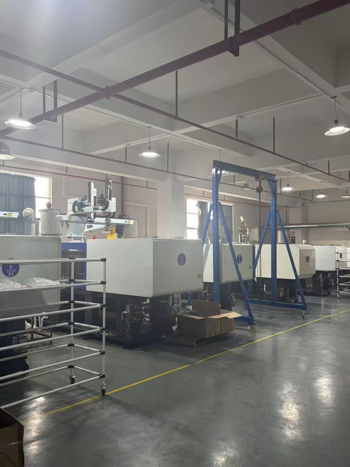 Row of injection-moulding machines with a stainless trolley in the foreground.