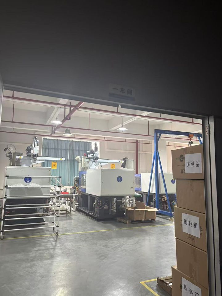 Moulding workshop seen through a doorway, with turnover boxes stacked beside the machines.