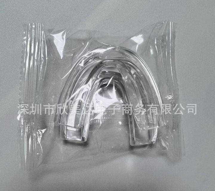A clear handle-less night guard sealed in a polybag.
